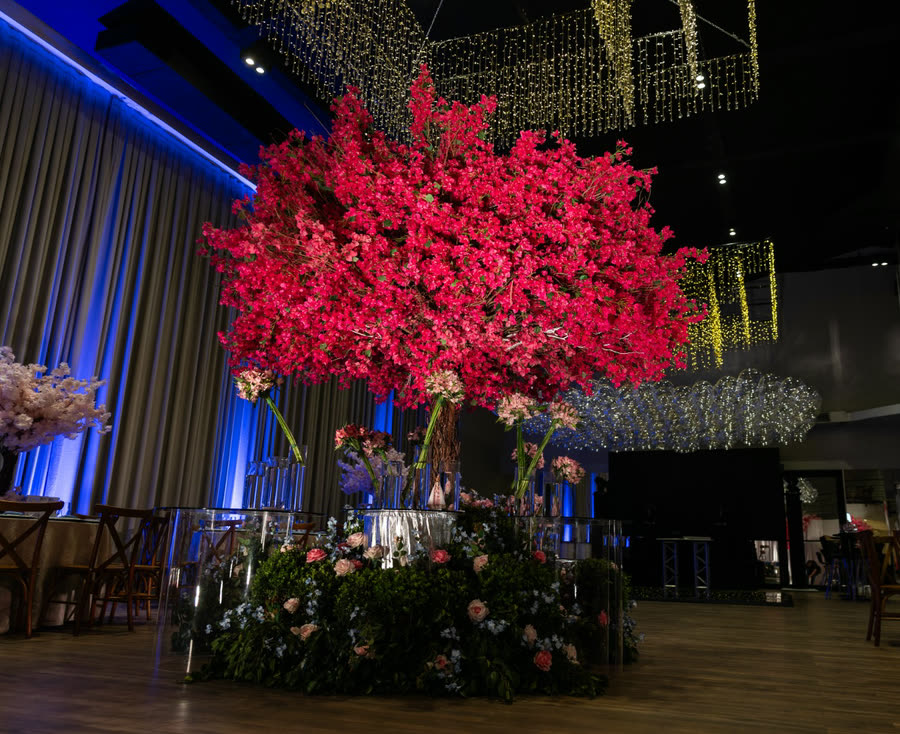 Árvore de flor pink sobre a mesa de vidro, sob a cortina de luzes do salão